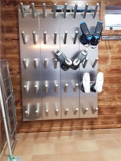 Ein moderner Schuhhalter aus Metall an einer Wand. Darauf hängen mehrere Paar Schuhe in unterschiedlichen Größen.