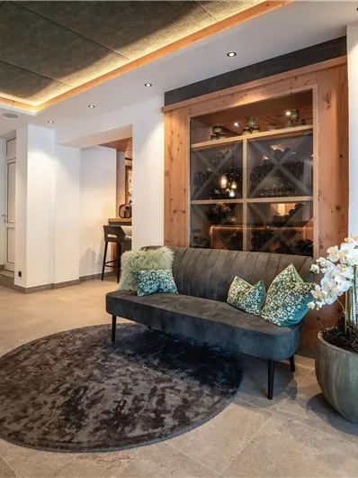 Een moderne foyer met een stijlvol bank en elegante kussens. Op de achtergrond zijn planten en een aantrekkelijke bar te zien.