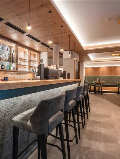 Een moderne bar met een elegante houten inrichting en stijlvolle stoelen. Zacht licht creëert een uitnodigende sfeer.