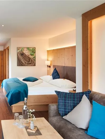 Een moderne hotelkamer met twee bedden en een gezellige zithoek. De wanden zijn voorzien van houten panelen en een groen kunstwerk.