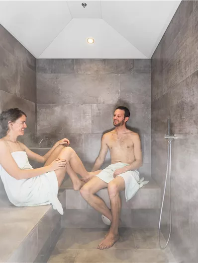 A modern steam bath with two people. The atmosphere is relaxing and steamy.