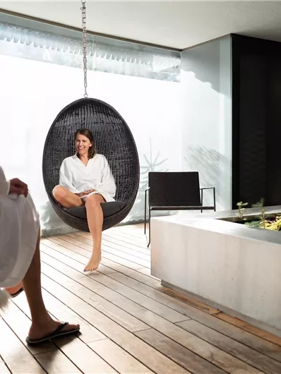 Een ontspannende wellnessruimte met twee mensen in badjassen. Ze zitten in schommelstoelen en genieten van de rustige sfeer.