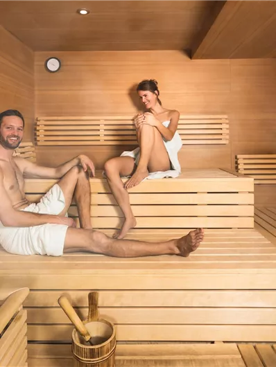 A few relaxed people in a modern sauna. The wooden shelves and the steam create a pleasant atmosphere.