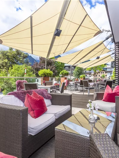 An elegant terrace with modern furniture and red cushions. Generous sunshades provide shade and a pleasant atmosphere.