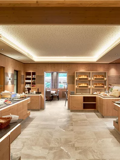 Een elegante eetzaal met houten meubels en een uitgebreid ontbijtbuffet. Heldere ramen zorgen voor een uitnodigende sfeer.