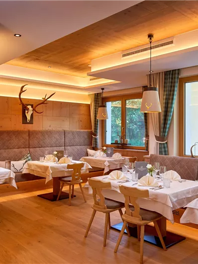 Een modern restaurant met houten elementen en elegante tafelaankledingen. Grote ramen zorgen voor veel licht en een mooi uitzicht naar buiten.