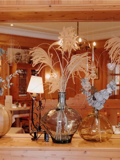 Eine stilvolle Dekoration in einem Restaurant mit mehreren Vasen und Trockenblumen. Der Holzrahmen verleiht der Szene eine gemütliche Atmosphäre.