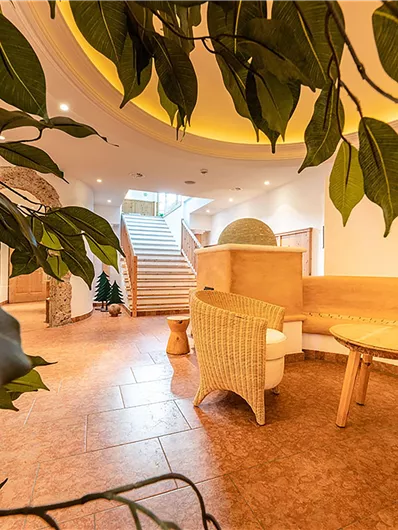 Ein eleganter Entspannungsbereich mit modernen Möbeln und einer warmen Atmosphäre. Im Hintergrund sind Treppen und dezente Pflanzen zu sehen.