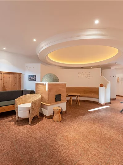 Ein moderner Wellnessbereich mit gemütlichen Möbeln. Er bietet eine entspannende Atmosphäre mit warmem Licht und Holzdetails.