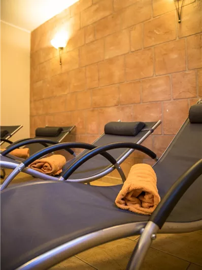 Ontspannen ligstoelen met oranje handdoeken in een warme kamer. De muren zijn in zachte aardetinten gehouden, wat een gezellige sfeer creëert.