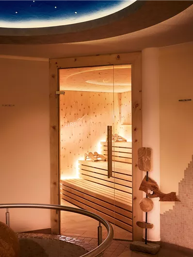 Een heldere wellnessruimte met een sauna en zachte verlichting. De ruimte geeft een gevoel van ontspanning en rust.