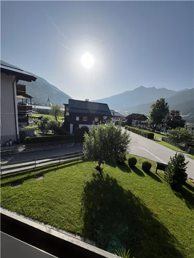 A sunny day in the mountains with green meadows and houses. The landscape is peaceful and inviting.