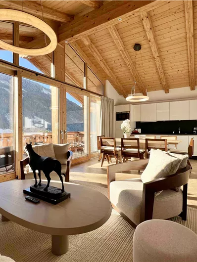 Ein modernes Wohnzimmer mit Holzdecken und großen Fenstern. Im Vordergrund steht ein runder Tisch mit einem dekorativen Tiermodell.