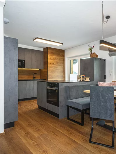 Moderne keuken met elegante meubels en grote ramen. De ruimte is helder en uitnodigend, ideaal om te koken en te eten.