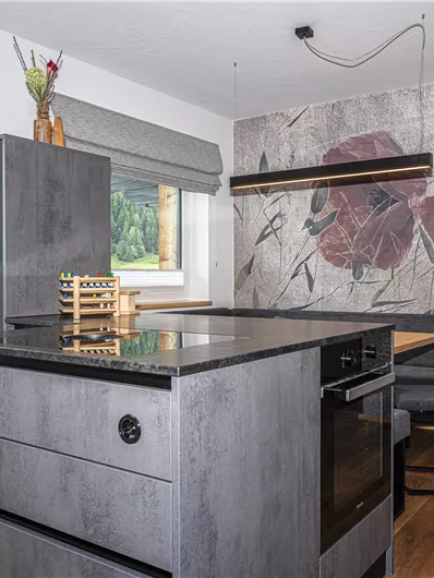 Een moderne keuken met een centrale kookeiland en elegante meubels. Aan de muur bevindt zich een decoratief bloemenpatroon.