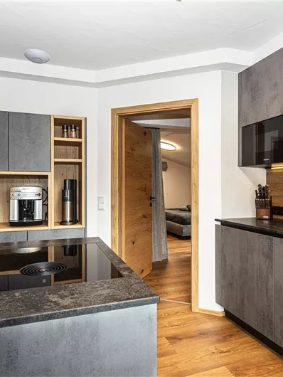 Een moderne keuken met een elegante werkblad en houten details. De ruimte is goed verlicht en opent zich naar een woonruimte.