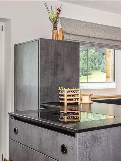 Moderne keuken met een centraal kookeiland en uitzicht op de omringende bergen. Grote ramen zorgen voor veel licht en een uitnodigende sfeer.