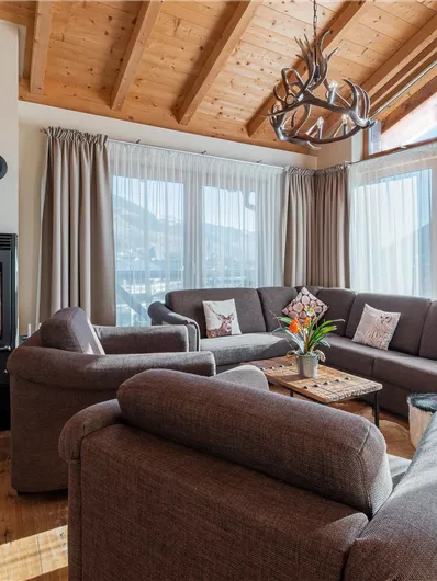 A cozy living area with a modern seating corner and a fireplace. Large windows provide plenty of daylight and a nice view of the surroundings.