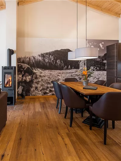 A modern living room with an open kitchen. The room has wooden floors and a cozy atmosphere.