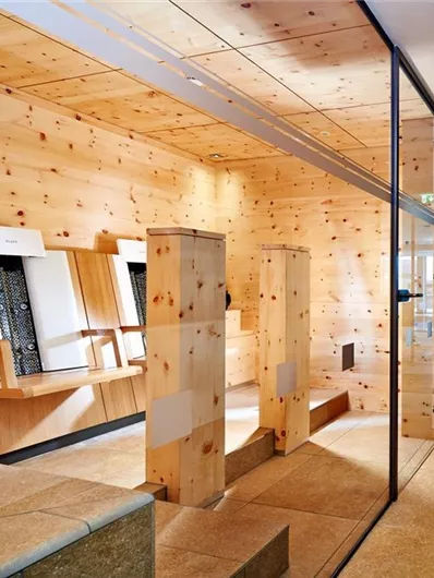 Ein moderner Raum mit Holzverkleidung und großen Fenstern. Der Bereich strahlt eine ruhige und einladende Atmosphäre aus.