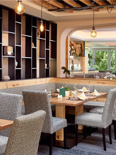 Een modern restaurant met een gezellige sfeer. De inrichting is stijlvol en harmonisch, met houten meubels en grote ramen die veel licht binnenlaten.