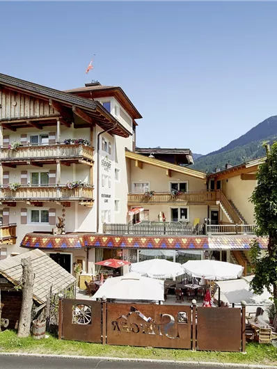 Een modern hotel met meerdere verdiepingen in een mooi berglandschap. De omgeving is groen en uitnodigend, ideaal voor een ontspannen vakantie.