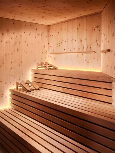 Een moderne sauna met houten planken en zachte, warmgekleurde verlichting. De ruimte straalt een ontspannende sfeer uit.