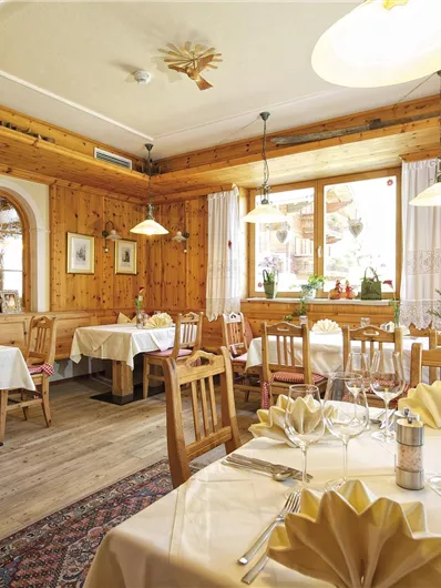 Een gezellig restaurant met houten wanden en tafelkleden. De tafels zijn elegant gedekt en creëren een uitnodigende sfeer.
