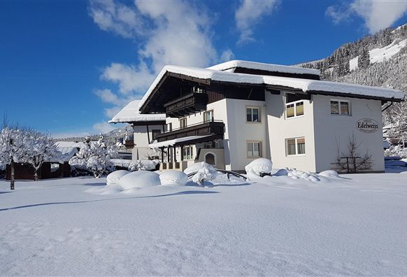 A beautiful house in the snow, surrounded by a winter landscape. The clear sky and the snow-covered trees create an idyllic atmosphere.
