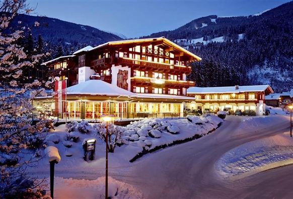 Een gezellige hotel in de bergen, omgeven door sneeuwwitte landschappen. De verlichting zorgt voor een gastvrije sfeer bij schemering.