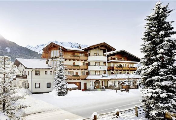 Een charmant hotel in een besneeuwd winterlandschap. Omgeven door bergen en sparren.